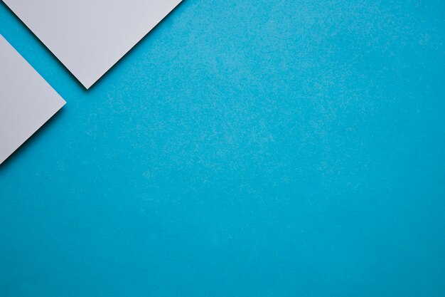 Dos papeles de cartón gris en la esquina de fondo azul