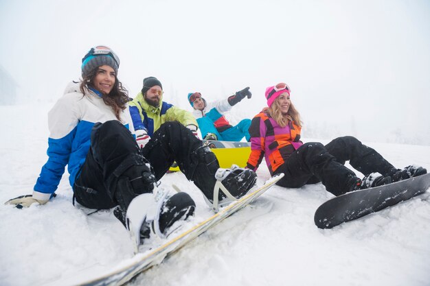 Dos parejas divirtiéndose y haciendo snowboard.