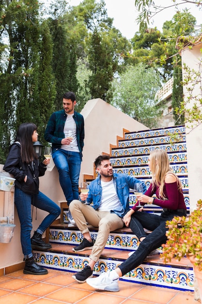 Dos parejas jóvenes disfrutando de bebidas en la escalera