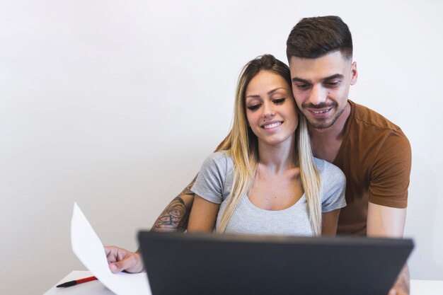 Dos pares preciosos que usan la computadora portátil contra el fondo blanco