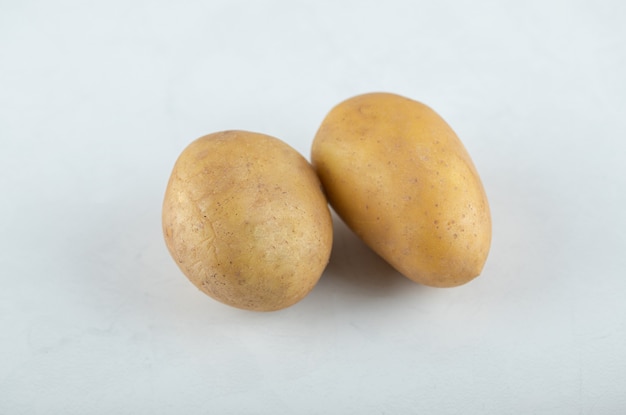 Dos patatas frescas sobre fondo blanco.
