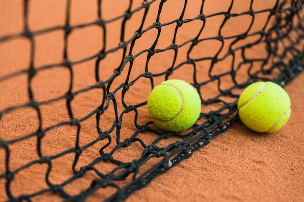 Dos pelotas de tenis cerca de la red negra en el suelo