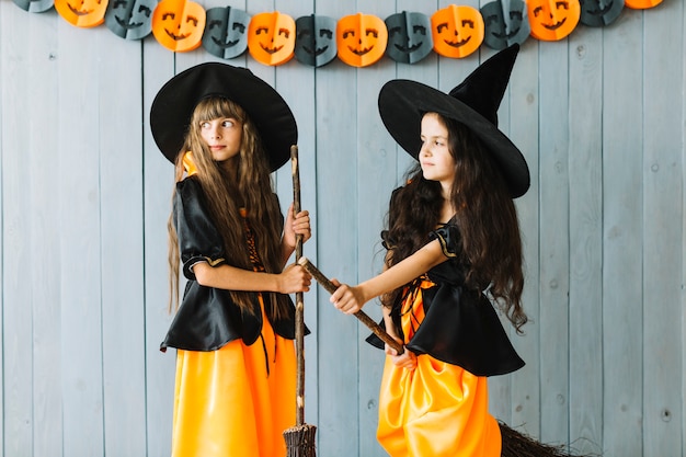 Dos pequeñas brujas con escobas en Halloween