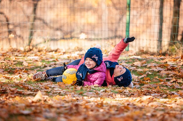 Las dos pequeñas niñas jugando en hojas de otoño