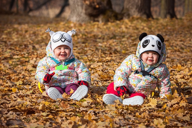 Las dos pequeñas niñas sentadas en hojas de otoño