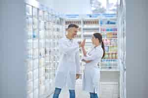 Foto gratuita dos personas en batas de laboratorio sintiéndose bien y sonriendo