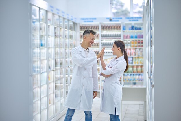 Dos personas en batas de laboratorio sintiéndose bien y sonriendo