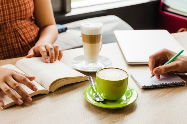 Dos personas estudiando en café con taza de café y café con leche
