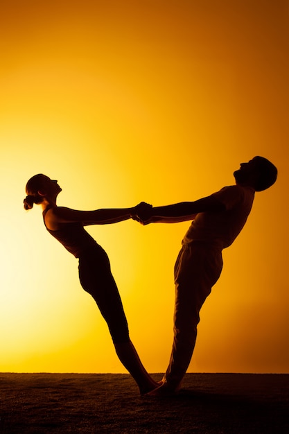 Dos personas practicando yoga en la luz del atardecer