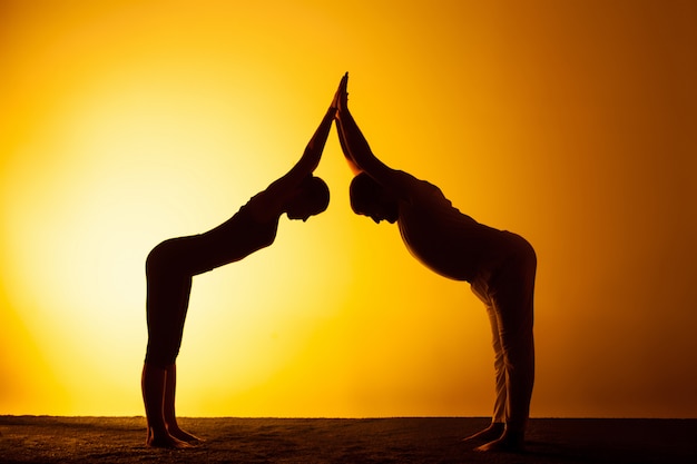 Foto gratuita dos personas practicando yoga en la luz del atardecer