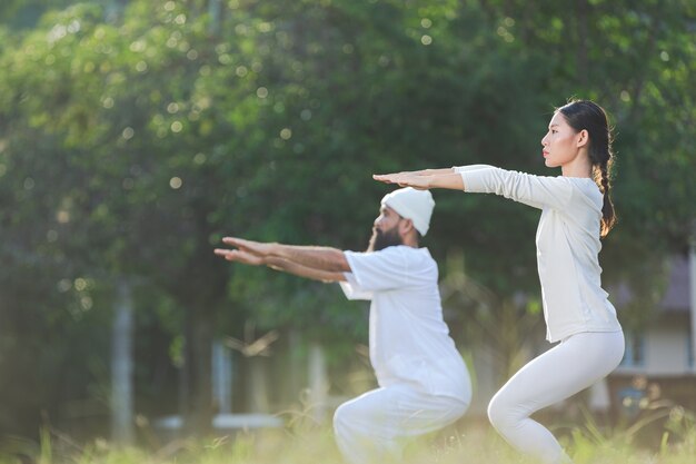 Dos personas en traje blanco haciendo yoga en la naturaleza
