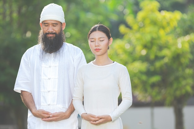 Dos personas en traje blanco meditando en la naturaleza