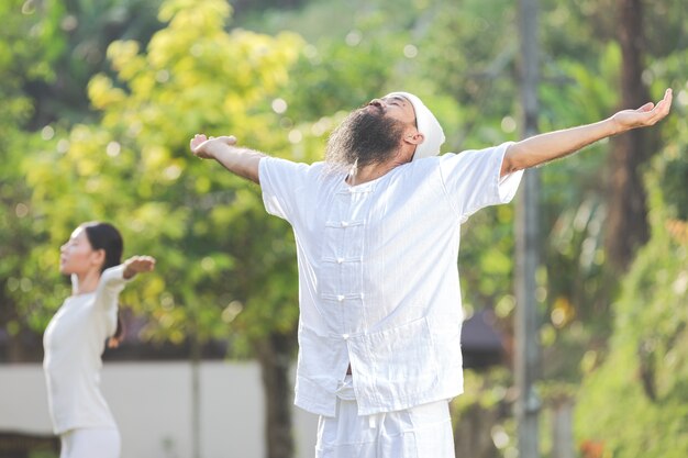 Dos personas en traje blanco meditando en la naturaleza