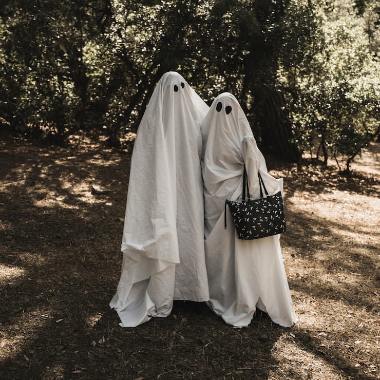 Foto gratuito dos personas en trajes de fantasmas abrazándose unos a otros en el bosque