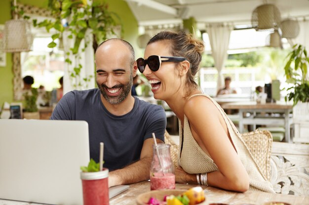 Dos personas usando laptop juntos y divirtiéndose.