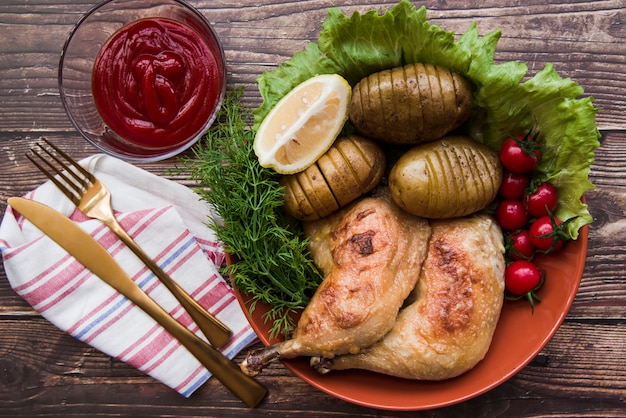 Dos piernas de pollo a la parrilla con frutas y verduras en un tazón