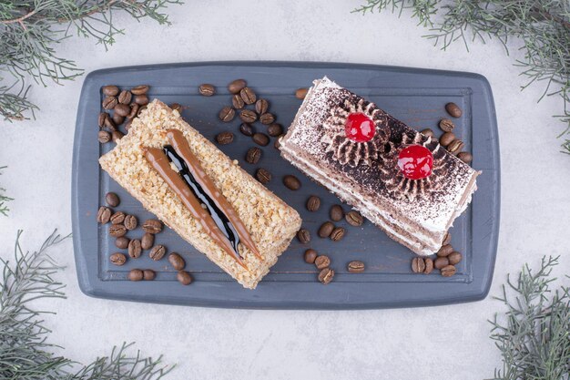 Dos rebanadas de pasteles en un plato oscuro con granos de café.