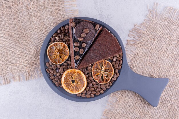 Dos rebanadas de tortas de chocolate con granos de café y rodajas de naranja. Foto de alta calidad