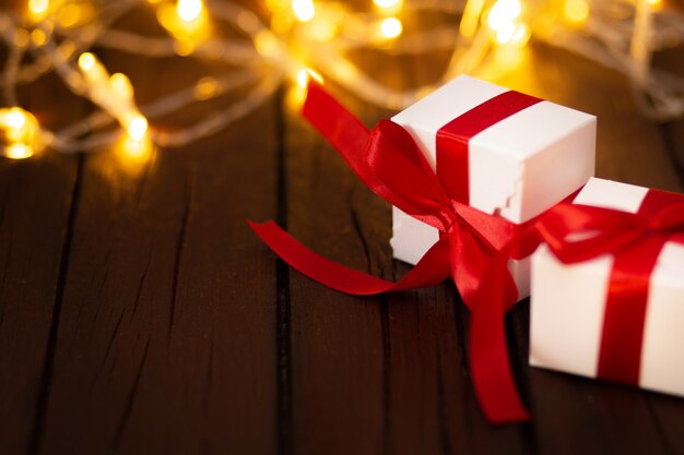 Dos regalos de navidad en una mesa de madera con luces bokeh