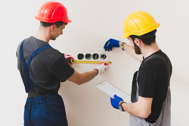 Dos reparadores haciendo medidas en la pared