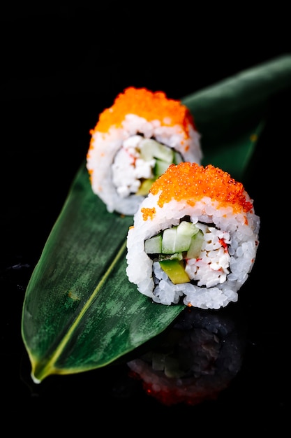 Dos rollos de sushi en una hoja verde en el espacio negro.