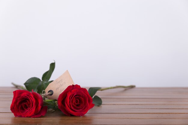 Dos rosas rojas con etiqueta en una mesa