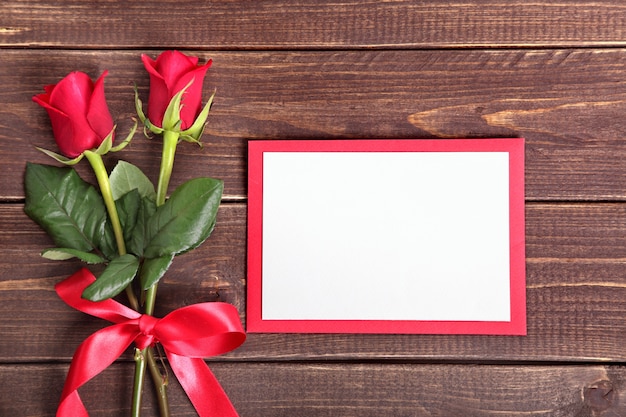 Dos rosas y una tarjeta para san valentín sobre madera