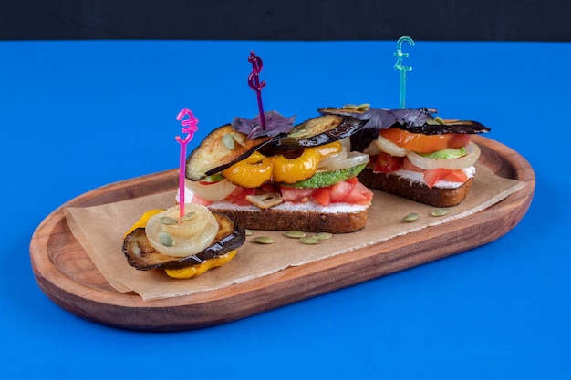 Dos sabrosas tostadas con verduras fritas en placa de madera