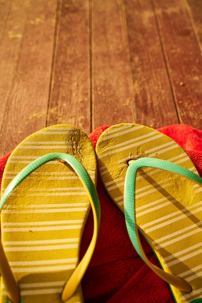 dos sandalias amarillas y una toalla roja sobre madera