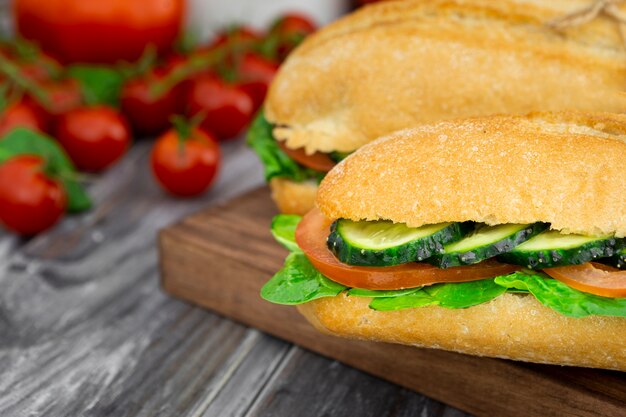 Dos sándwiches con rodajas de pepino y tomates desenfocados.