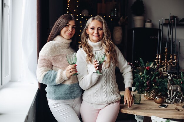 Dos señoras en ropa cómoda de invierno sosteniendo gafas elegantes mientras están de pie cerca una de la otra