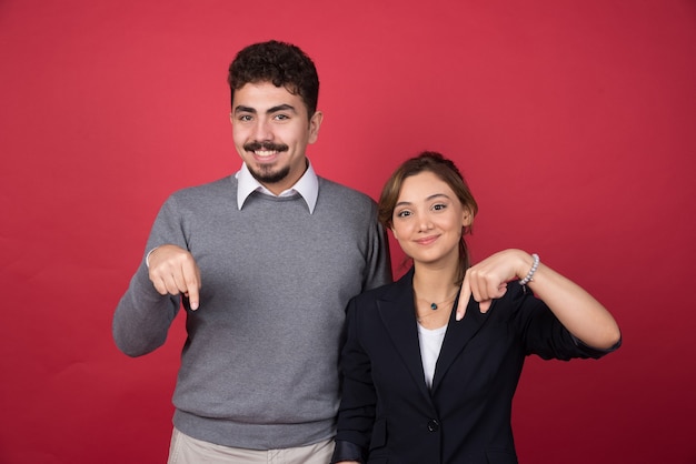 Dos socios comerciales dando apuntando hacia abajo en la pared roja