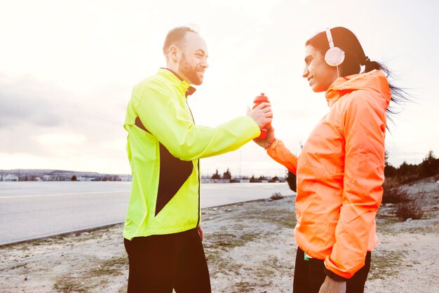 Dos sonriente atleta sosteniendo una botella de agua