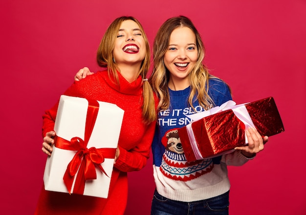 Foto gratuita dos sonrientes hermosas mujeres en elegantes suéteres con grandes cajas de regalo