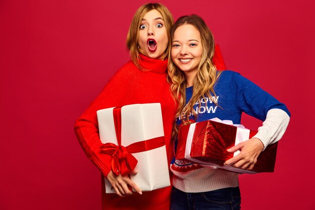 Dos sonrientes hermosas mujeres en elegantes suéteres con grandes cajas de regalo