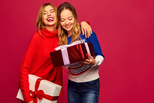 Dos sonrientes hermosas mujeres en elegantes suéteres con grandes cajas de regalo