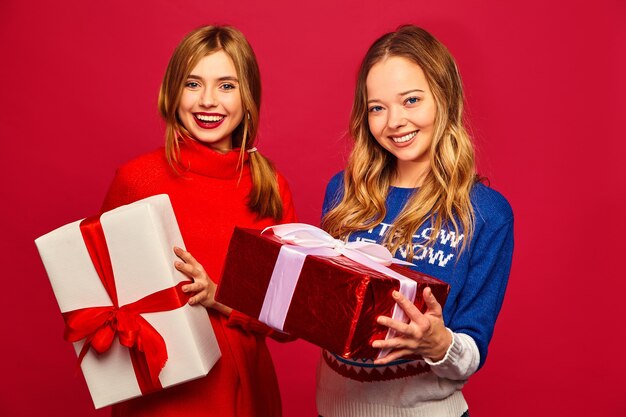 Dos sonrientes hermosas mujeres en elegantes suéteres con grandes cajas de regalo