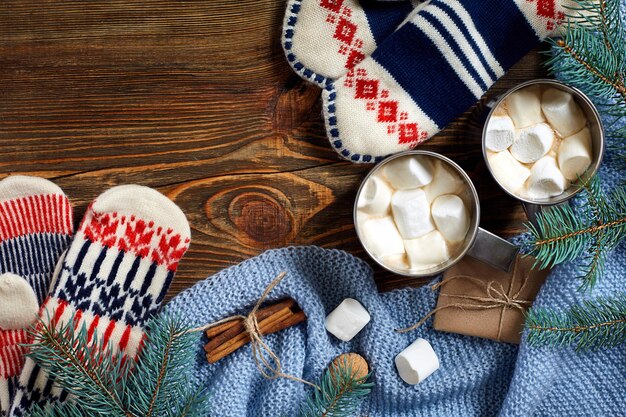Dos tazas de cacao caliente o chocolate con malvavisco, mitones, decoración navideña y abeto sobre fondo rústico de madera desde arriba. Estilo plano. Año nuevo 2018.