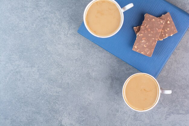 Dos tazas de café con bombones en el libro.