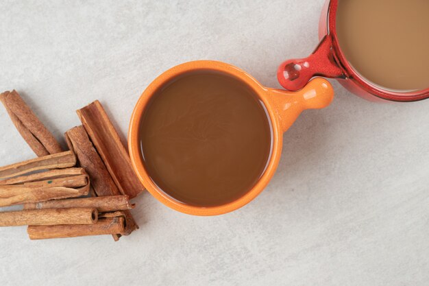 Dos tazas de café y canela sobre la superficie de mármol