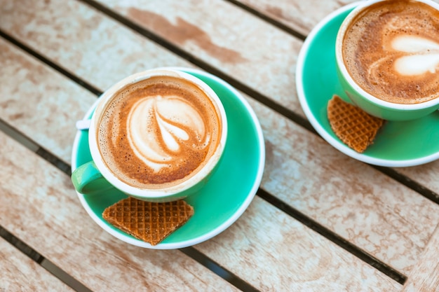 Dos tazas de café con forma de corazón, café con leche y gofres