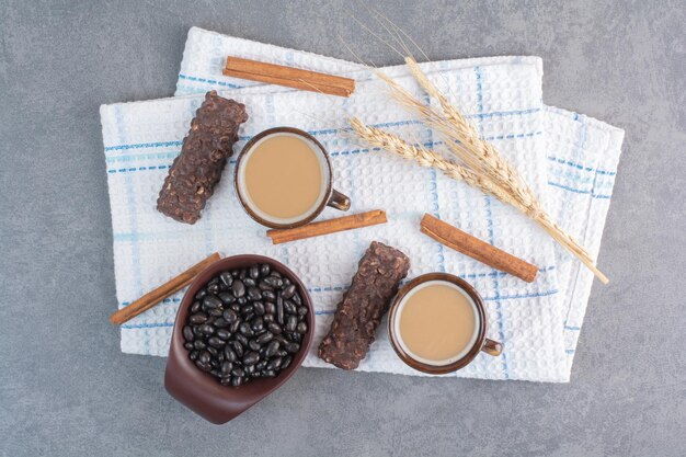 Dos tazas de café con hoja de papel y bombones sobre mantel