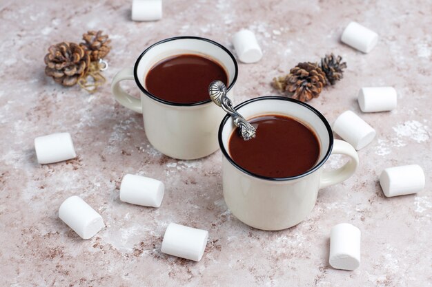 Dos tazas de chocolate caliente con malvaviscos en la mesa