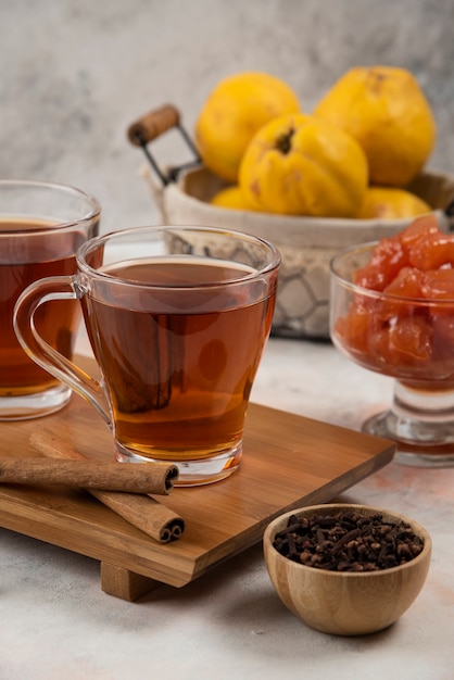 Dos tazas de té caliente y palitos de canela sobre tabla de madera.