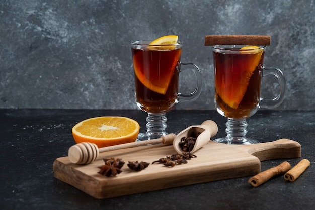 Dos tazas de té de cristal y con canela en rama y cucharón de madera.