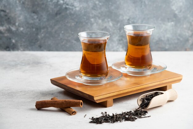 Dos tazas de té de cristal con canela en rama y tés a granel Foto de alta calidad