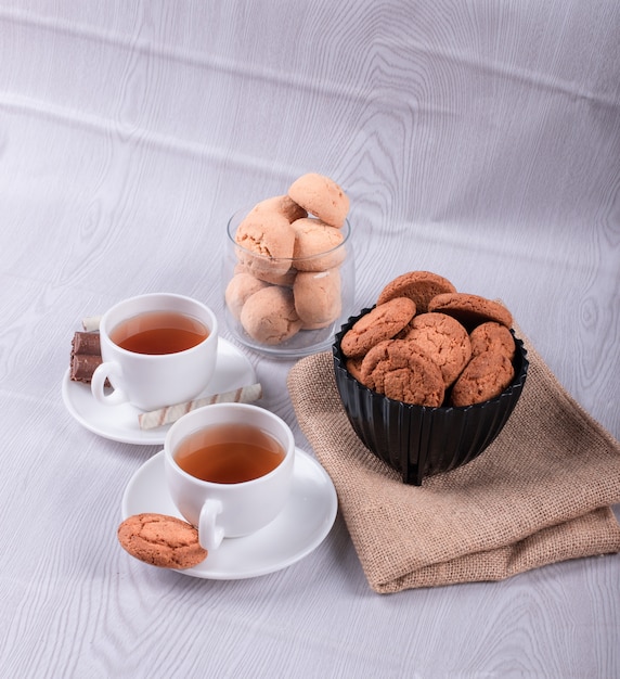 Foto gratuita dos tazas de té con galletas y chocolate.