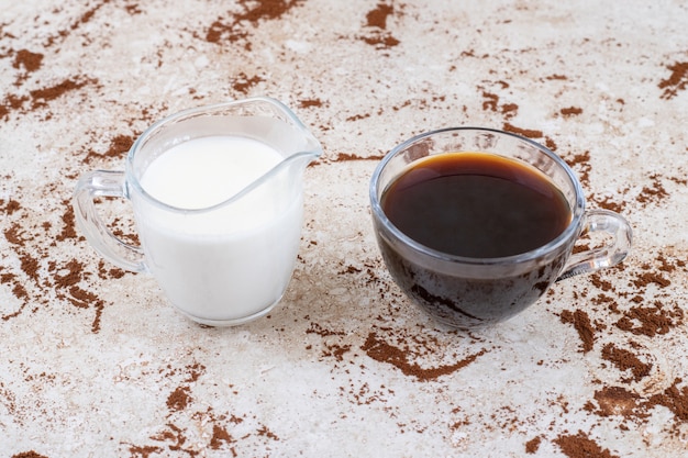 Dos tazas de té y leche sobre una superficie de mármol