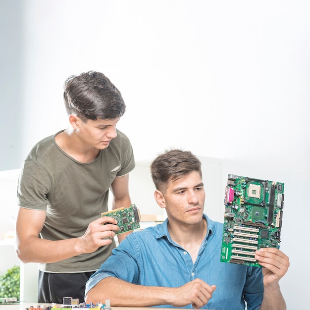 Foto gratuita dos técnicos masculinos que miran la placa madre