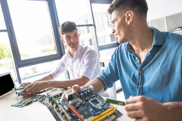Dos técnicos masculinos que reparan la placa base de la computadora